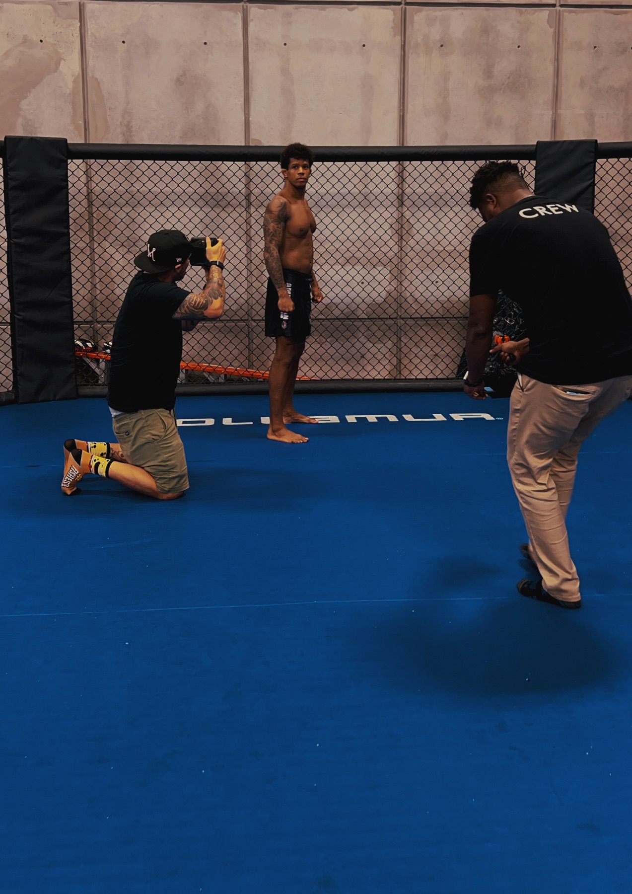 Production crew filming an athlete inside a training ring